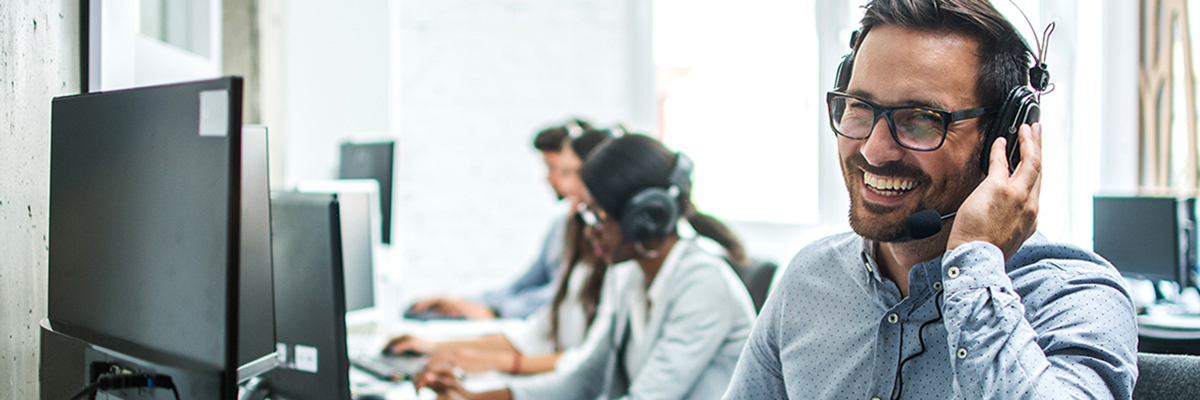Smiling handsome customer support operator with headset working in call center.